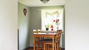 Un coin repas avec une table et des chaises en bois, une plante en pot et une fenêtre avec des rideaux.