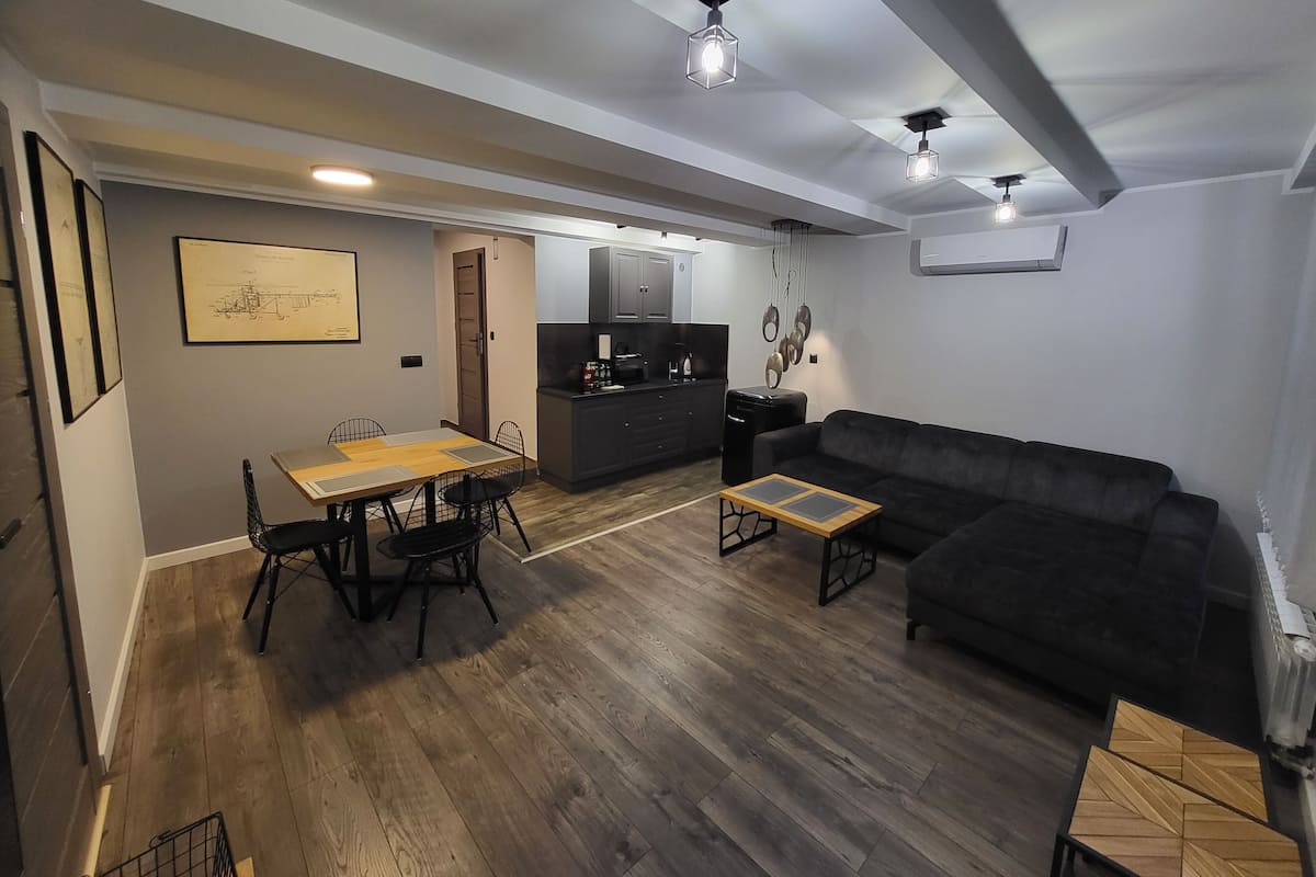 A modern living room with a dining table, sofa, and kitchen area.