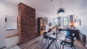 Eine moderne Küche mit Backsteinwand, Holzschränken und einem Essbereich mit Glastisch und Stühlen.