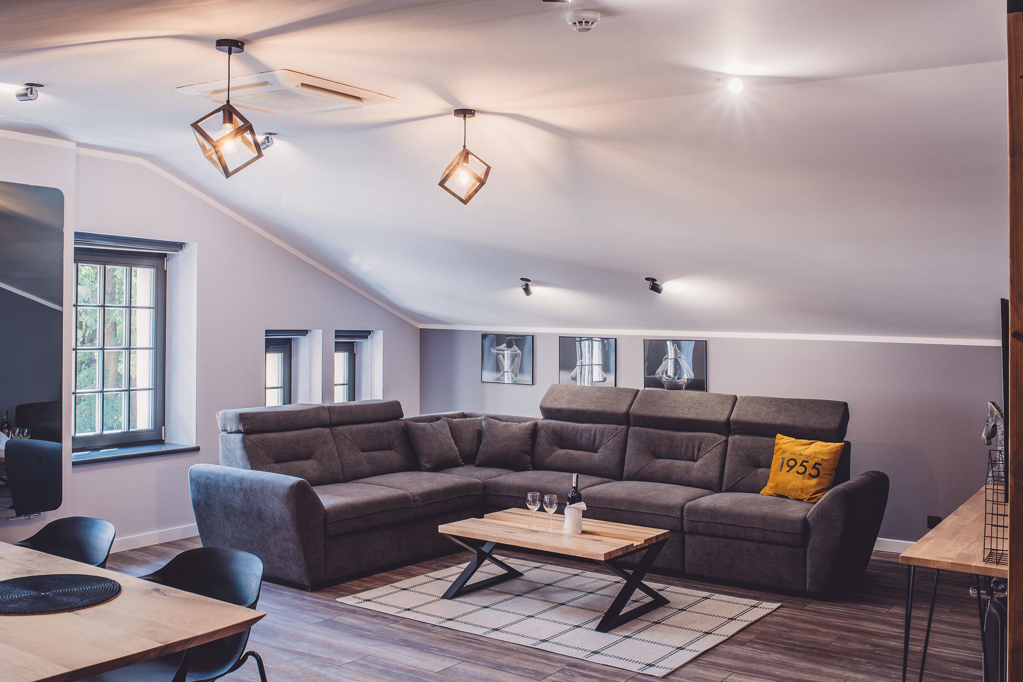 A modern living room with a sectional sofa, a coffee table, and pendant lighting.