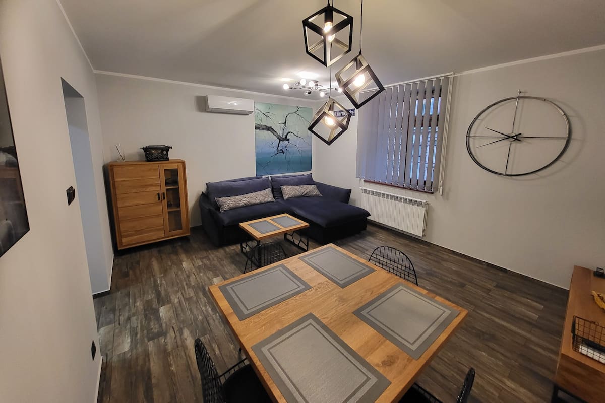A modern living room with a sofa, dining table, and a wooden cabinet.