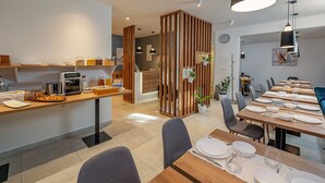 A modern dining area with wooden tables and chairs, a buffet station, and a decorative partition. - Seven Seas Residence (Split)