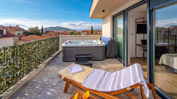 A balcony with a hot tub, a lounge chair, and a view of the cityscape. - Seven Seas Residence (Split)