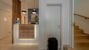 A reception area with a wooden reception desk, pendant lighting, a door, and a staircase. - Seven Seas Residence (Split)