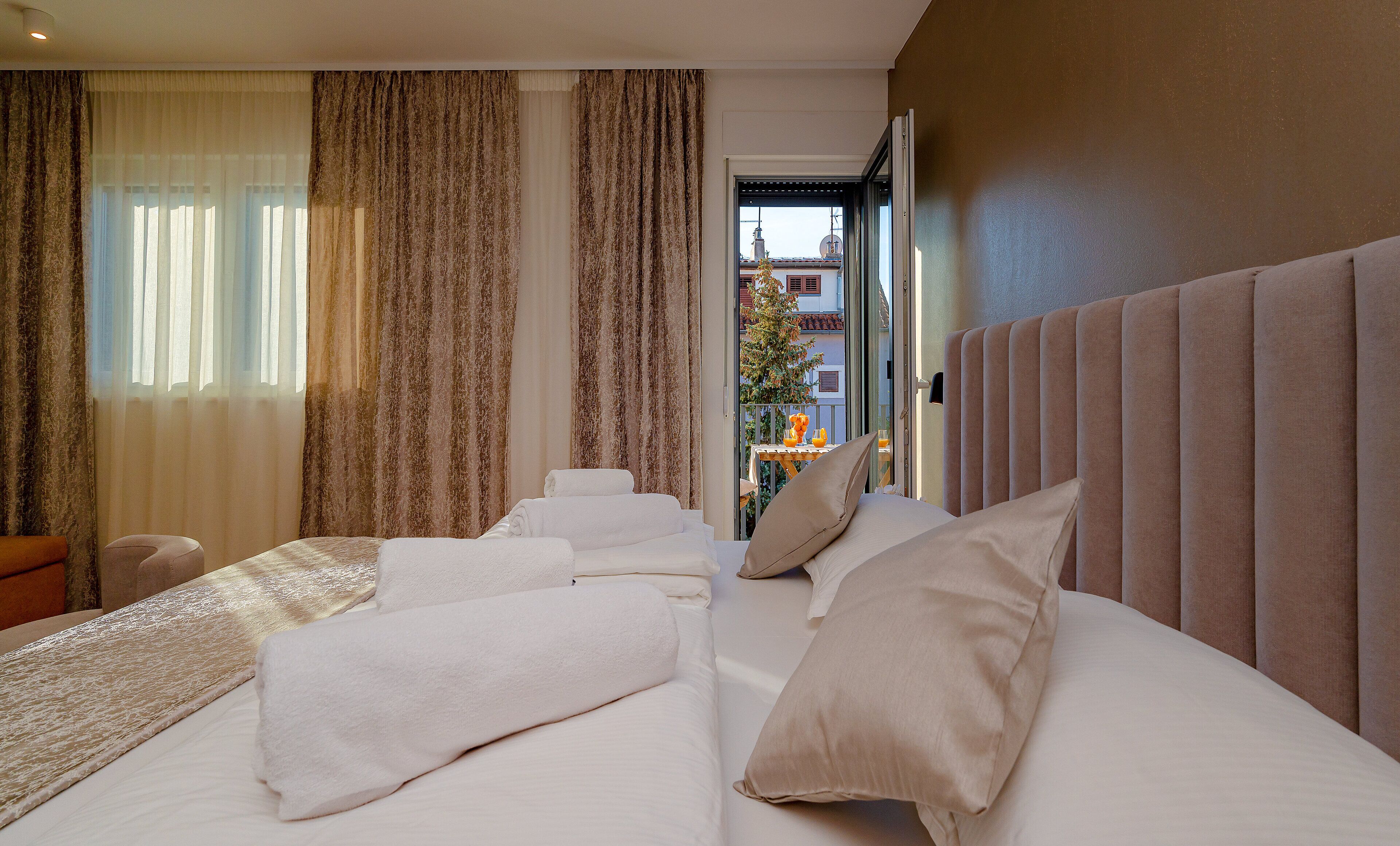 Ein Hotelzimmer mit einem großen Bett, einem kleinen Tisch mit Obstschale und Blick auf den Balkon.