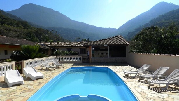 A swimming pool with lounge chairs, a hot tub, and a view of mountains. - Pousada Atlantica Recanto do Mar (Caraguatatuba)