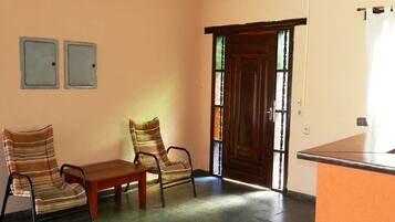 Una habitación con dos sillas a rayas, una mesa de madera y una puerta de madera con paneles de vidrio.