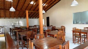 A spacious dining area with wooden tables and benches, high ceilings with exposed beams, and pendant lighting. - Pousada Atlantica Recanto do Mar (Caraguatatuba)