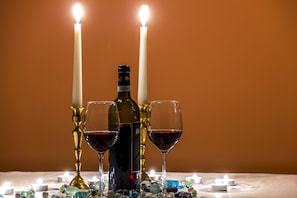 Uma mesa com uma garrafa de vinho, dois copos e duas velas acesas.