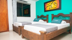 Een hotelkamer met twee houten bedden, elk voorzien van een kussen en een deken.