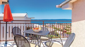 A balcony with a table and chairs, a red umbrella, and a view of the sea. - 2 bedroom cozy apartment in Novi Vinodolski (Novi Vinodolski)