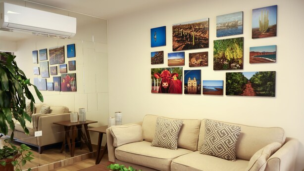 Un salon avec un canapé beige, une table basse et un mur décoré de divers tableaux encadrés.