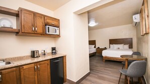 Une chambre d’hôtel de taille réduite, équipée d’une kitchenette, d’un lit, d’une table de chevet et d’une chaise.