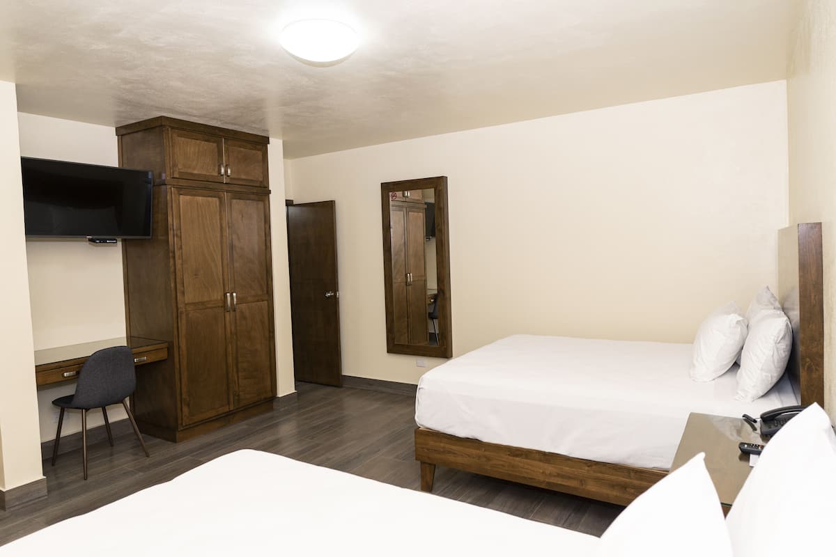 Une chambre d’hôtel équipée d’un lit, d’un bureau, d’une chaise, d’une armoire et d’un téléviseur fixé au mur.