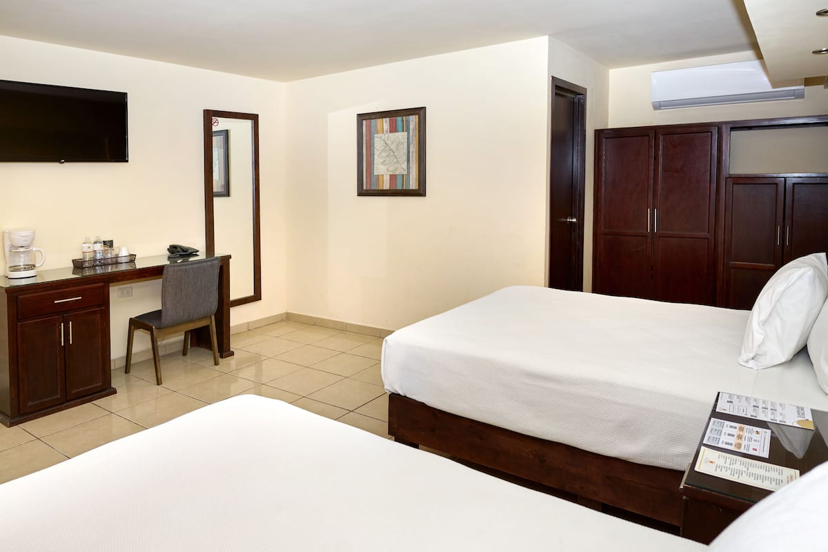 Une chambre d’hôtel avec deux lits, un bureau avec une chaise, une télévision et une armoire.