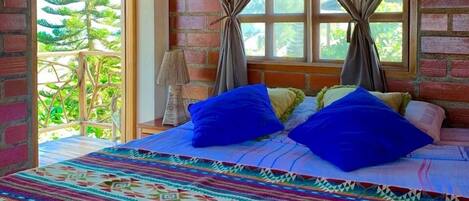A room with a bed, curtains, and a view of greenery.
