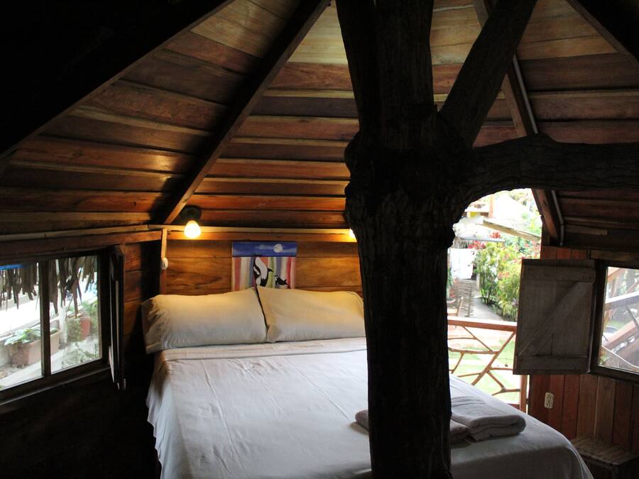 A wooden cabin bedroom with a bed, a window, and a wooden ceiling.
