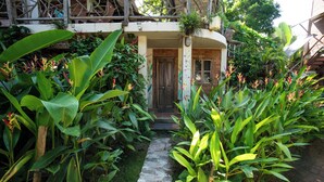 Un sentier de jardin mène à une porte en bois sur laquelle est apposée une plaque indiquant « Réception ».