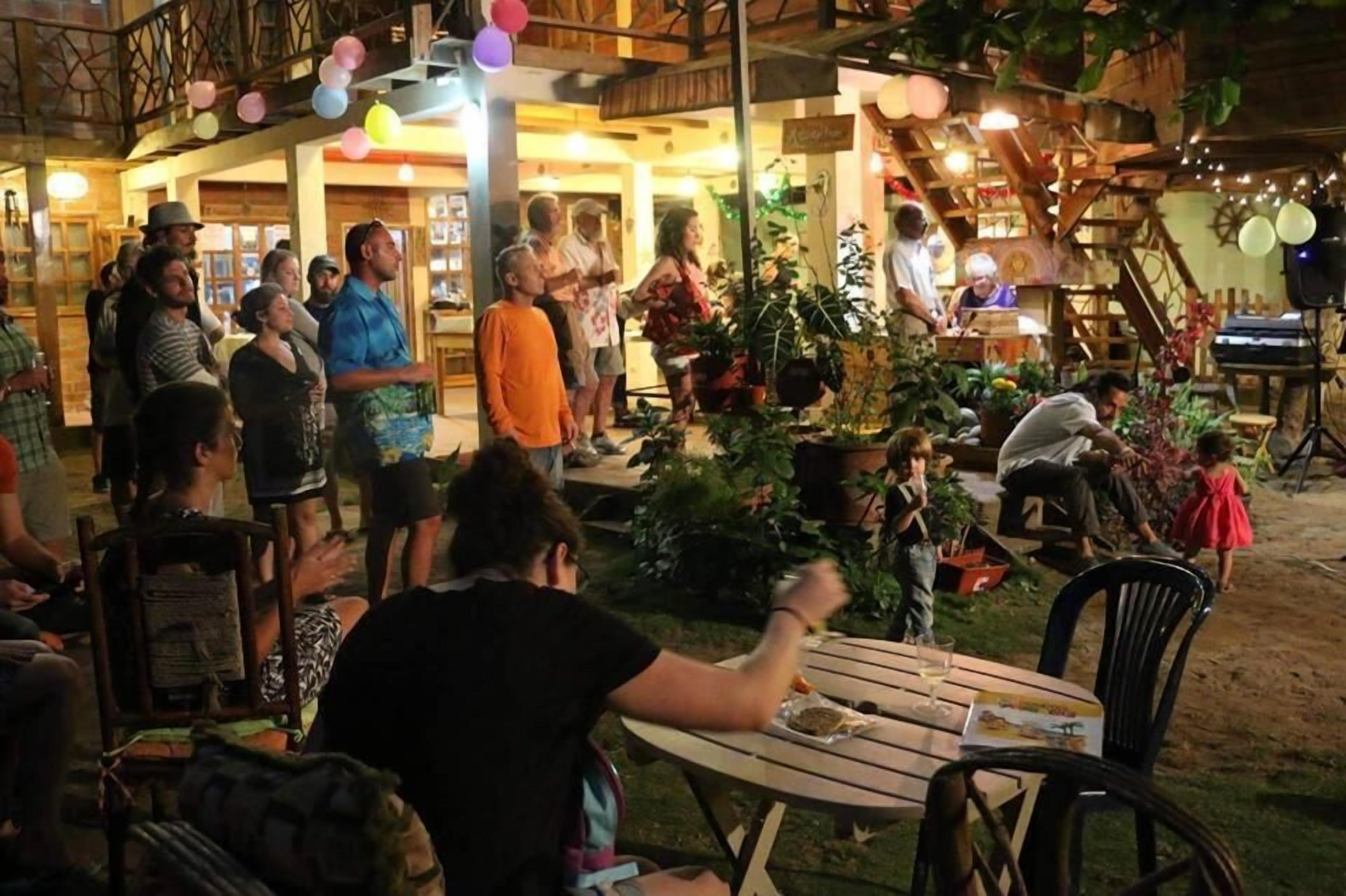 Un espace de restauration en plein air, avec des tables et des chaises, entouré de verdure et agrémenté d’une structure en bois rustique.