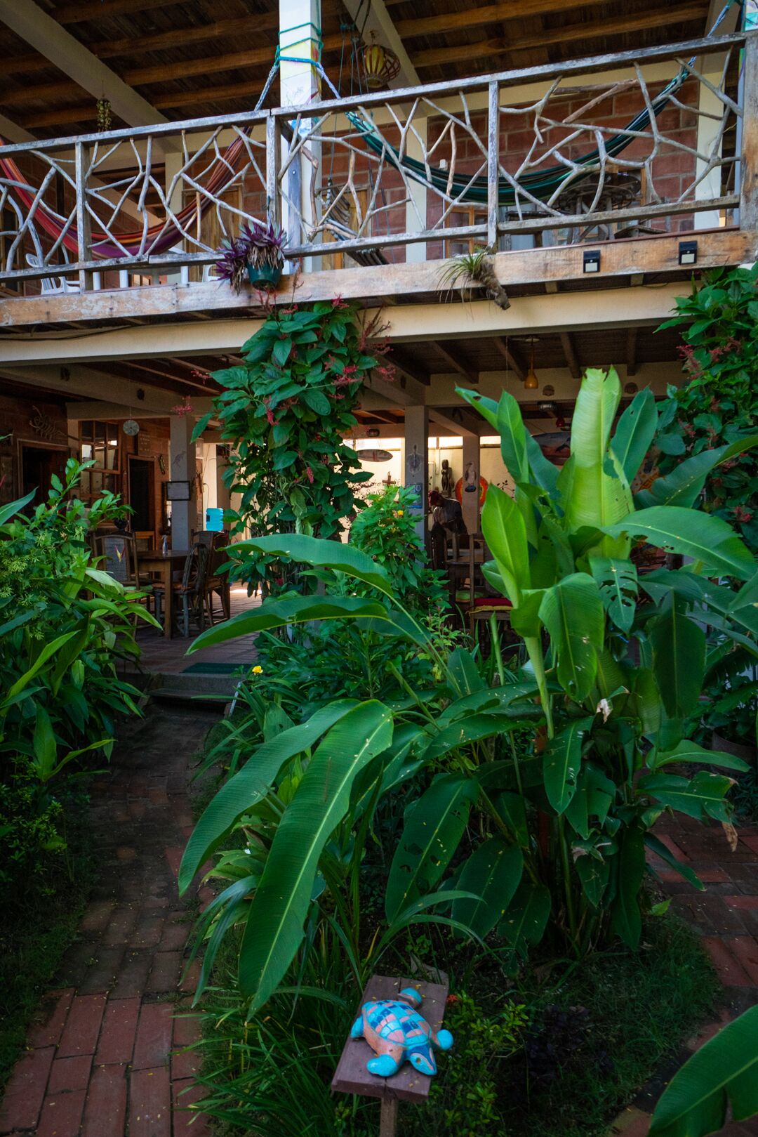 A covered outdoor area with a wooden deck, potted plants, and a small turtle sculpture.