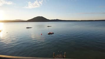 Un'acqua calma con barche, una collina in lontananza e un molo in primo piano.