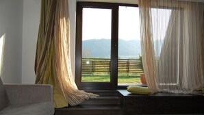 A room with a sofa, a bench, and a view of a balcony with a railing. - Wolf 2 (Zarnesti)