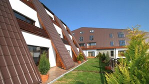 A modern building with a sloped roof, a well-maintained lawn, and potted plants. - Wolf 2 (Zarnesti)