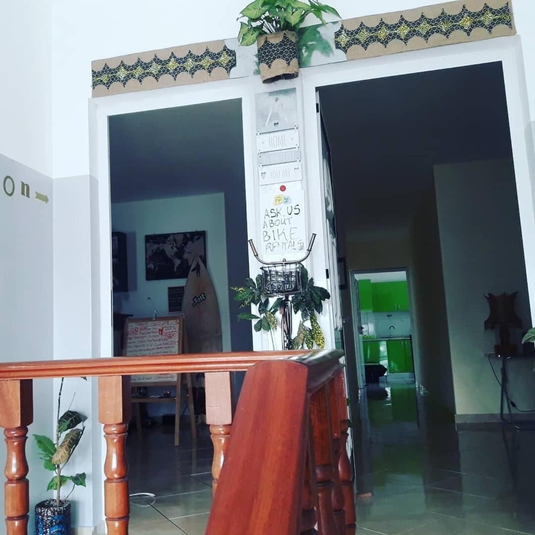 A hotel entrance with a wooden staircase, a sign offering bike rentals, and a glimpse of the interior including a kitchen area.