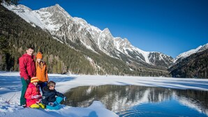 Una familia junto a un lago con montañas al fondo.