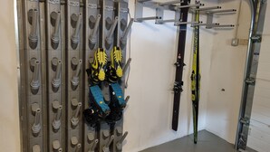 Zona de guardado para esquíes con varios soportes y un par de esquíes apoyados en la pared.
