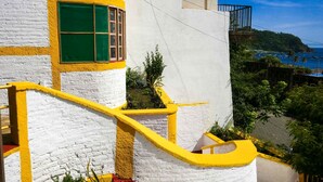 A white building with yellow accents and a green window. - Casa Ruth (San Juan del Sur)