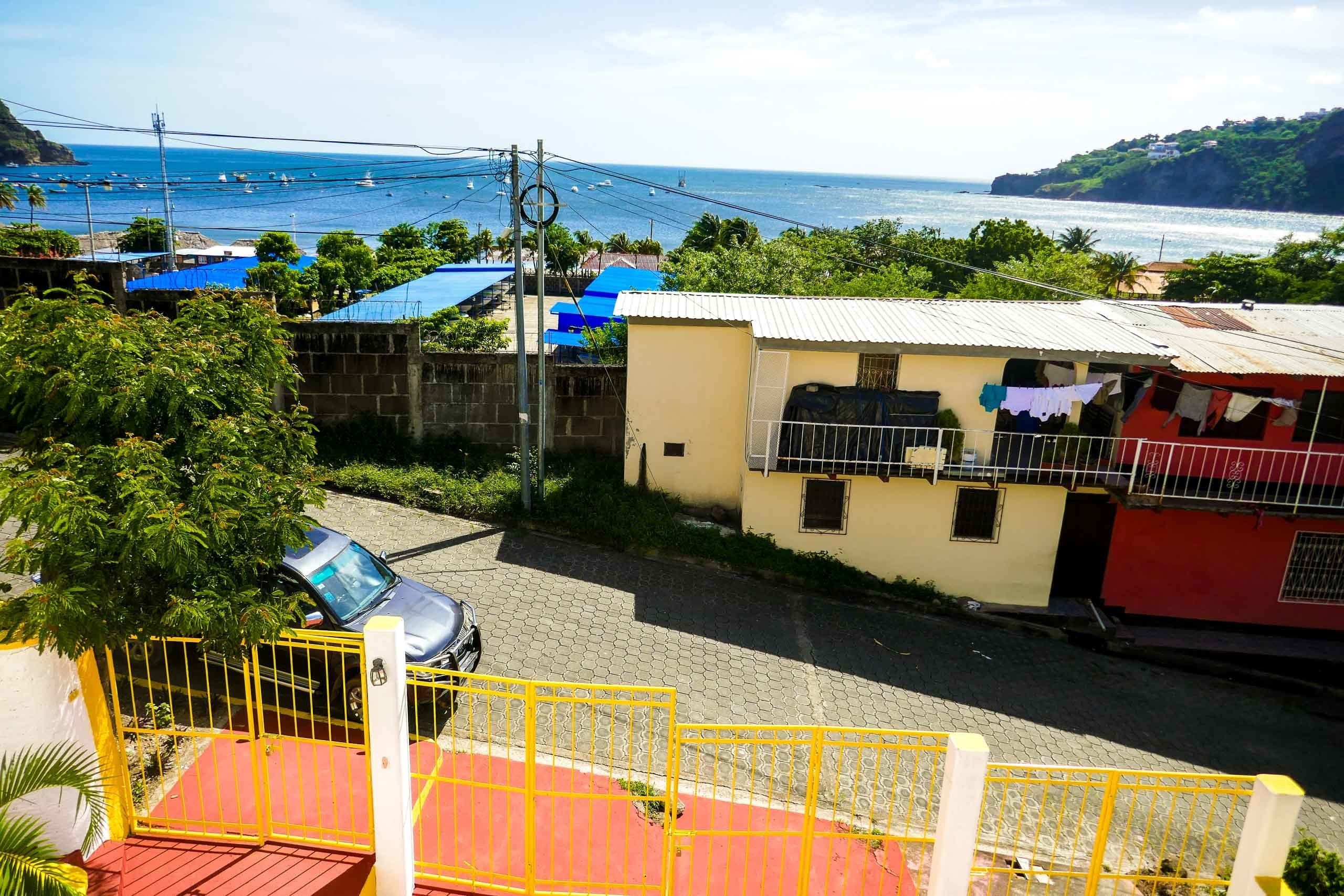 Un área residencial costera con casas, un coche aparcado y vista al mar.
