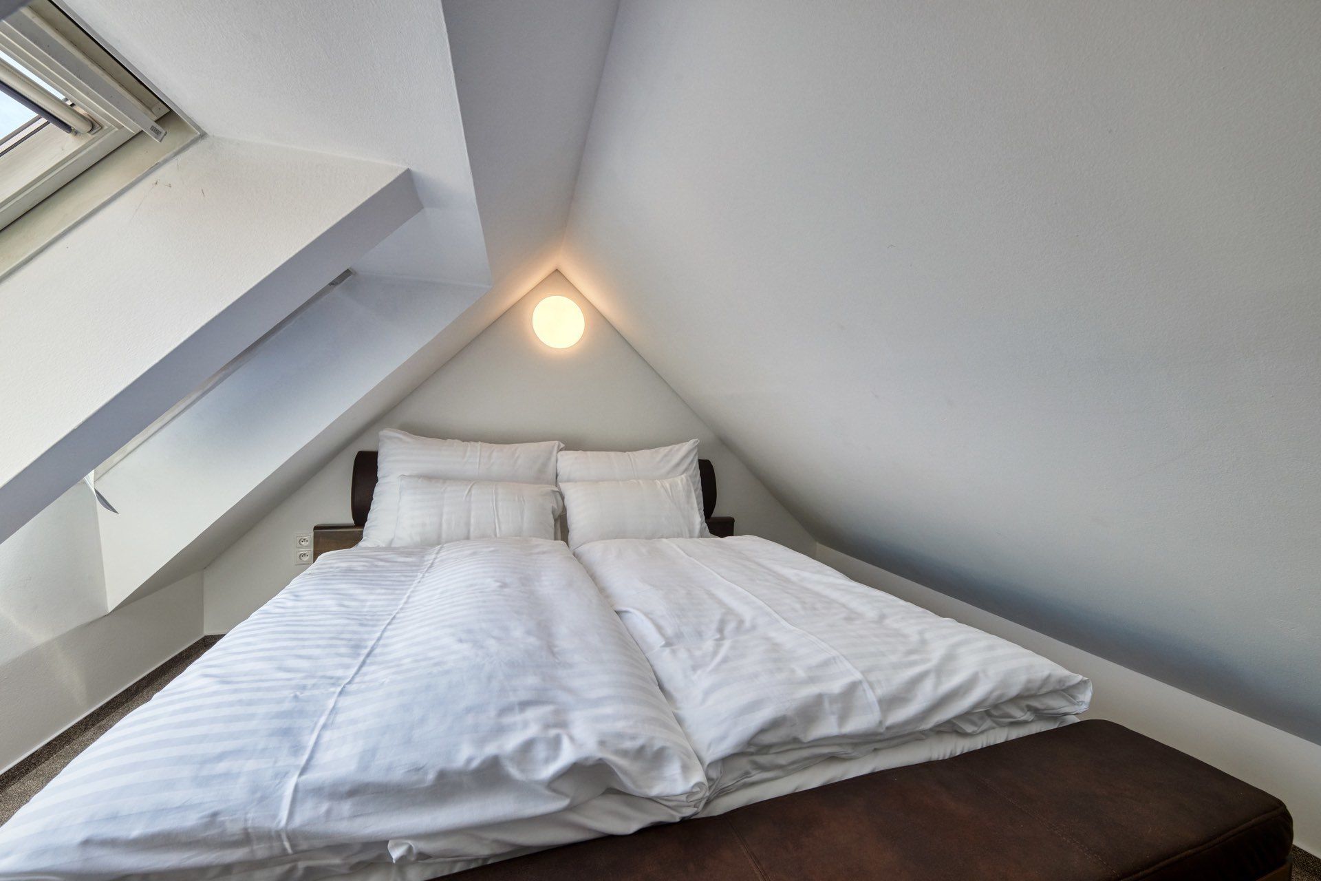 Un dormitorio con cama, almohadas y mesita de noche.