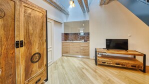 Una cocina moderna con armarios de madera, salpicadero de ladrillo y televisión empotrada.