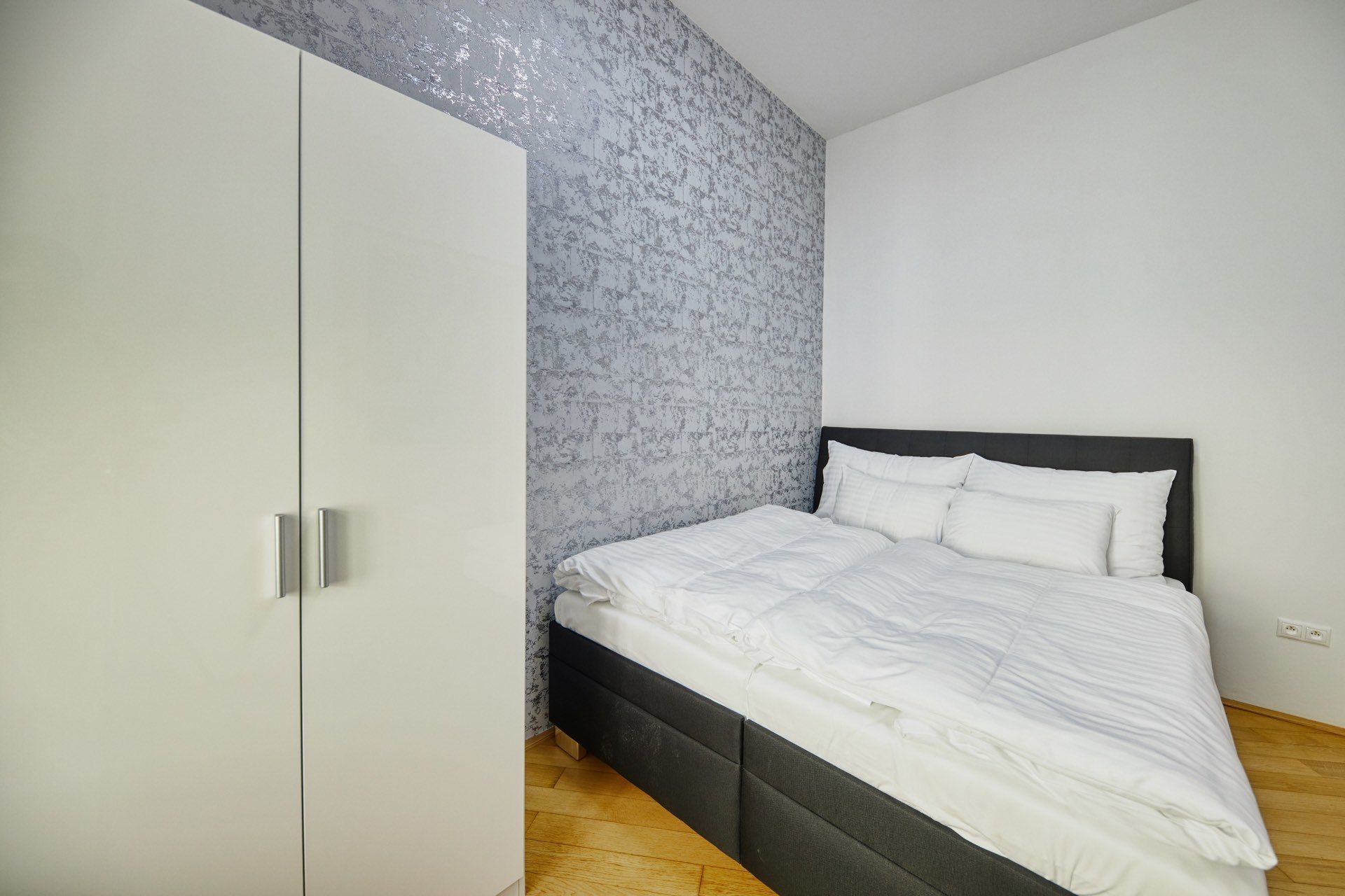 Une chambre à coucher avec un lit, une armoire et un mur décoré d’un motif.