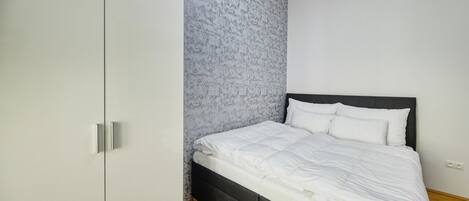 Une chambre à coucher avec un lit, une armoire et un mur décoré d’un motif.
