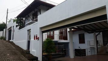 Two-story building with a flat roof and balcony on the upper floor, featuring a staircase and covered entryway.