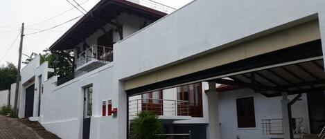 A two-story building with a covered entrance, a staircase, and a balcony with a metal railing.
