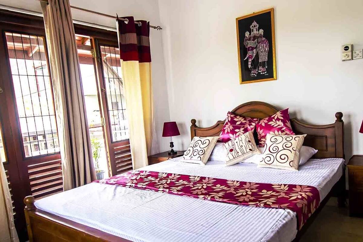 A neatly made bed with a floral bedspread, two bedside lamps, and a framed picture on the wall.