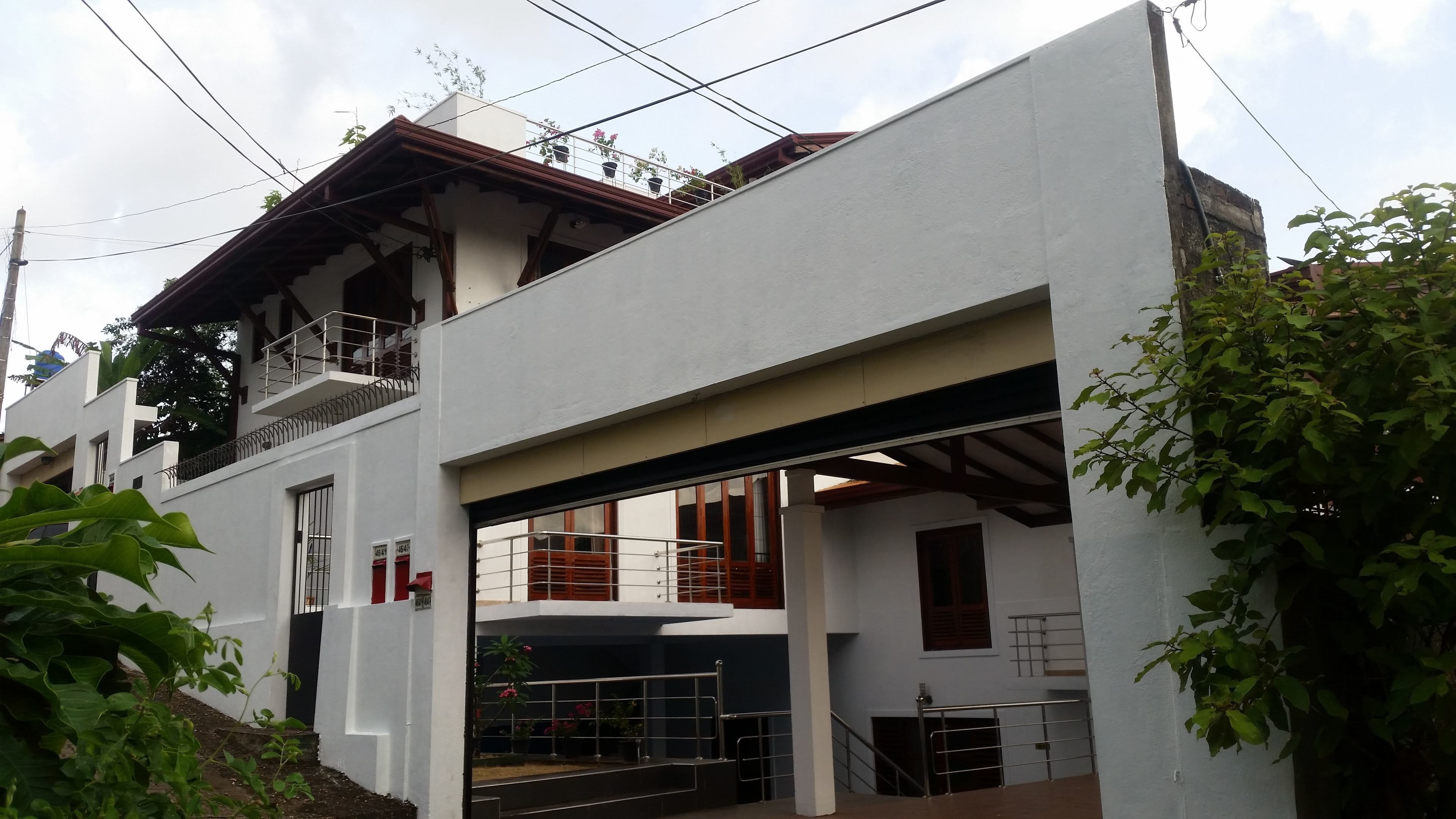 A modern two-story building with a balcony, a covered outdoor area, and a staircase leading to an upper level.
