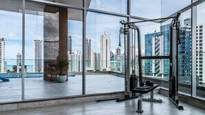 A spacious room with large windows offering a view of a city skyline and a body of water. - Best Accommodation Ocean View (Panama City)