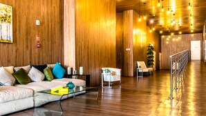 A modern lobby with wooden walls, a white sofa with colorful cushions, a glass coffee table, and a staircase with a railing. - Best Accommodation Ocean View (Panama City)