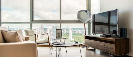 Una sala de estar moderna con un ventanal grande, un sofá, una mesa de centro, un televisor y una lámpara.