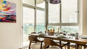 Een moderne eetruimte met een groot raam, een houten tafel en stoelen.