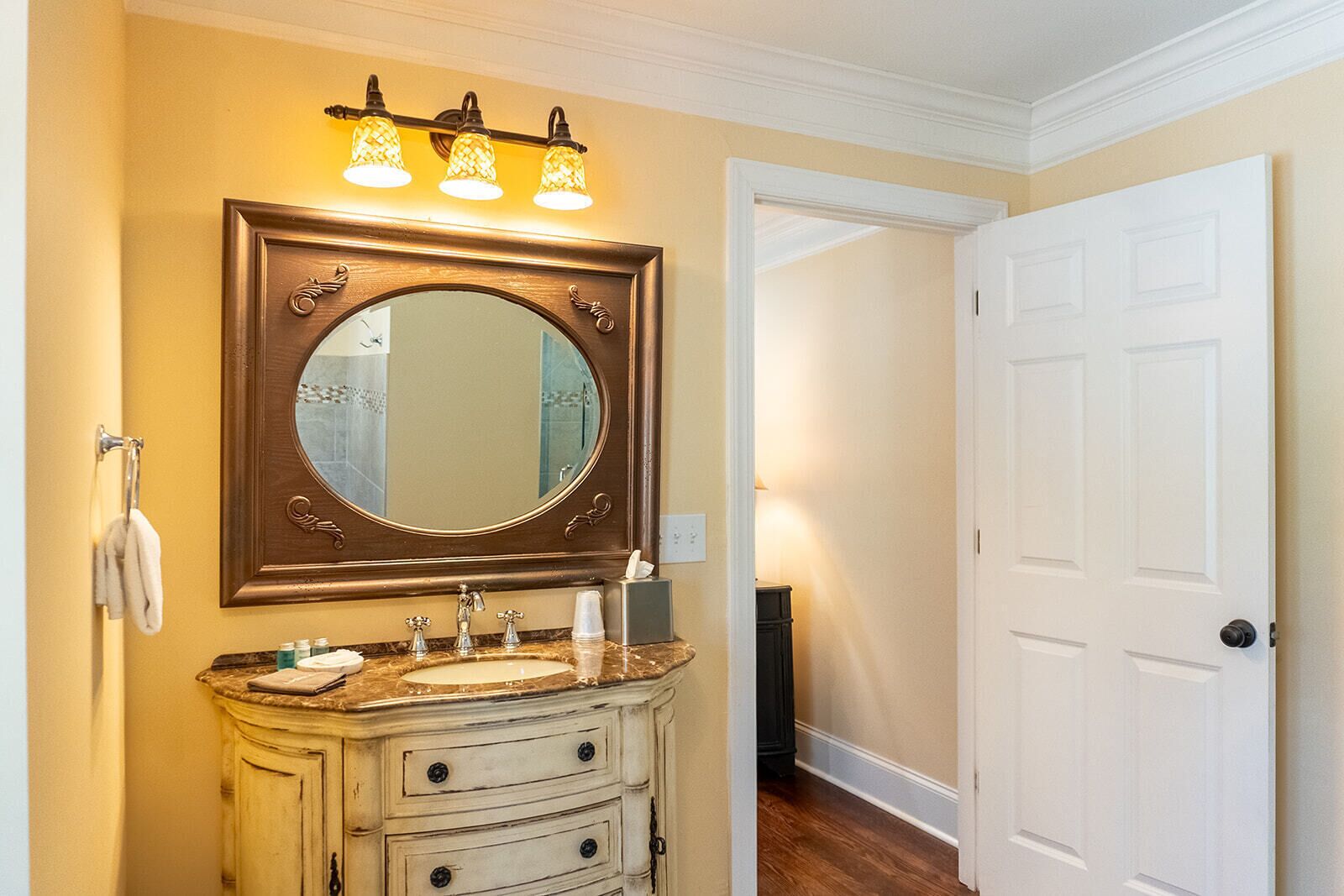 A bathroom with a large mirror, a vanity with a sink, and a towel rack.