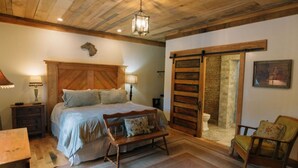 Una camera da letto con un letto in legno, una panca, una sedia, un comodino e un lampadario.