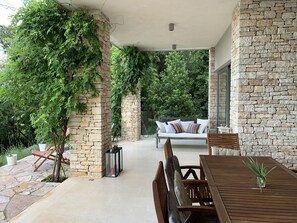 Relax in a serene outdoor space surrounded by lush greenery, complete with a dining table and comfortable seating area.