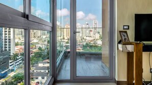 A balcony with a city view, a television, and a framed picture on a stand.