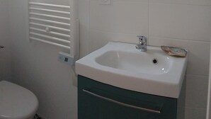 Een badkamer met een witte radiator, een wastafel met een kraan en een toilet.