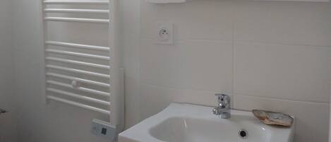 Une salle de bain avec un radiateur blanc, un lavabo avec un robinet et des toilettes.